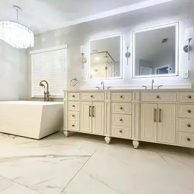 A master bathroom with a double vanity, backlit mirrors and a chandelier