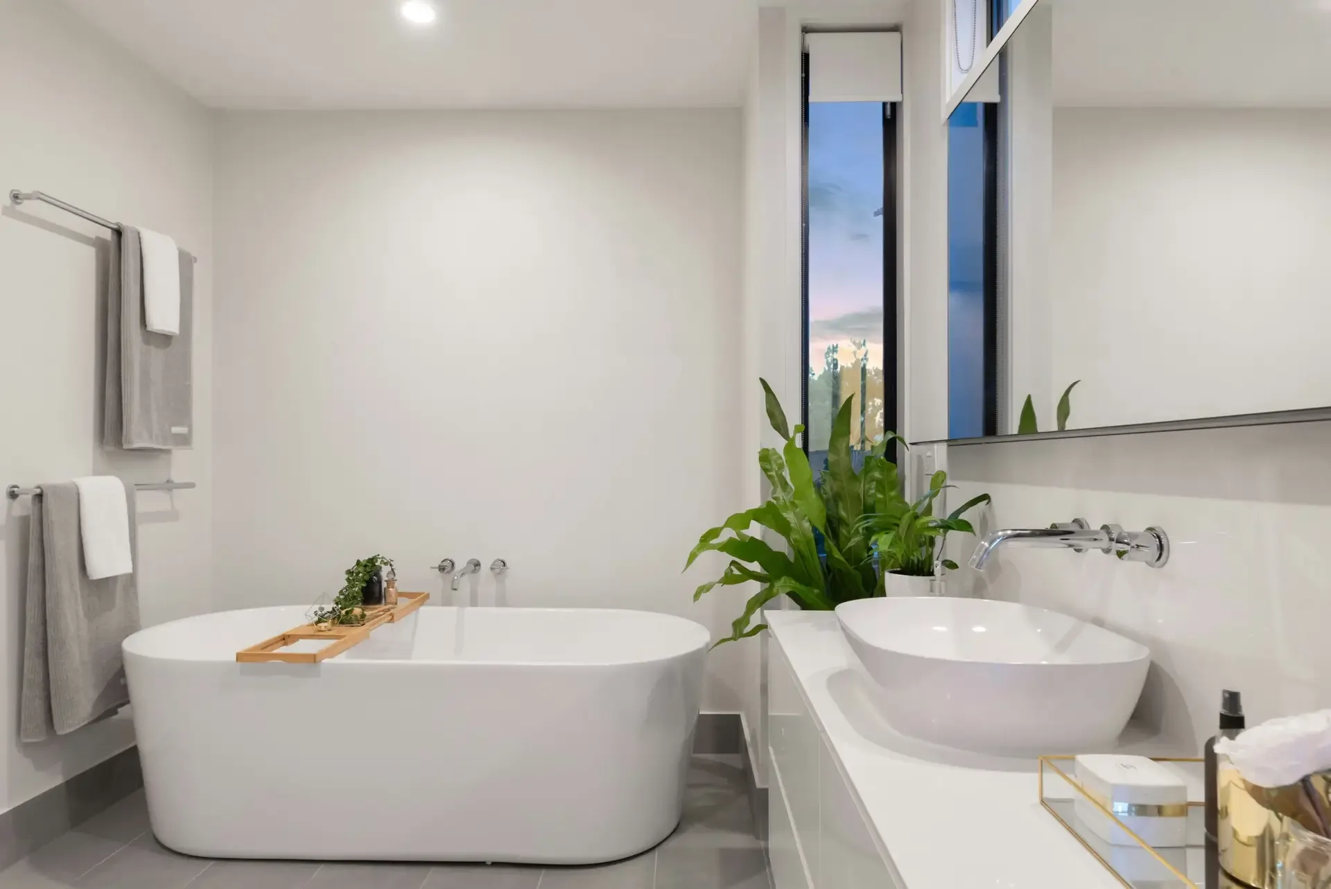 A bright bathroom with a freestanding tub, vessel sink and a window over the counter