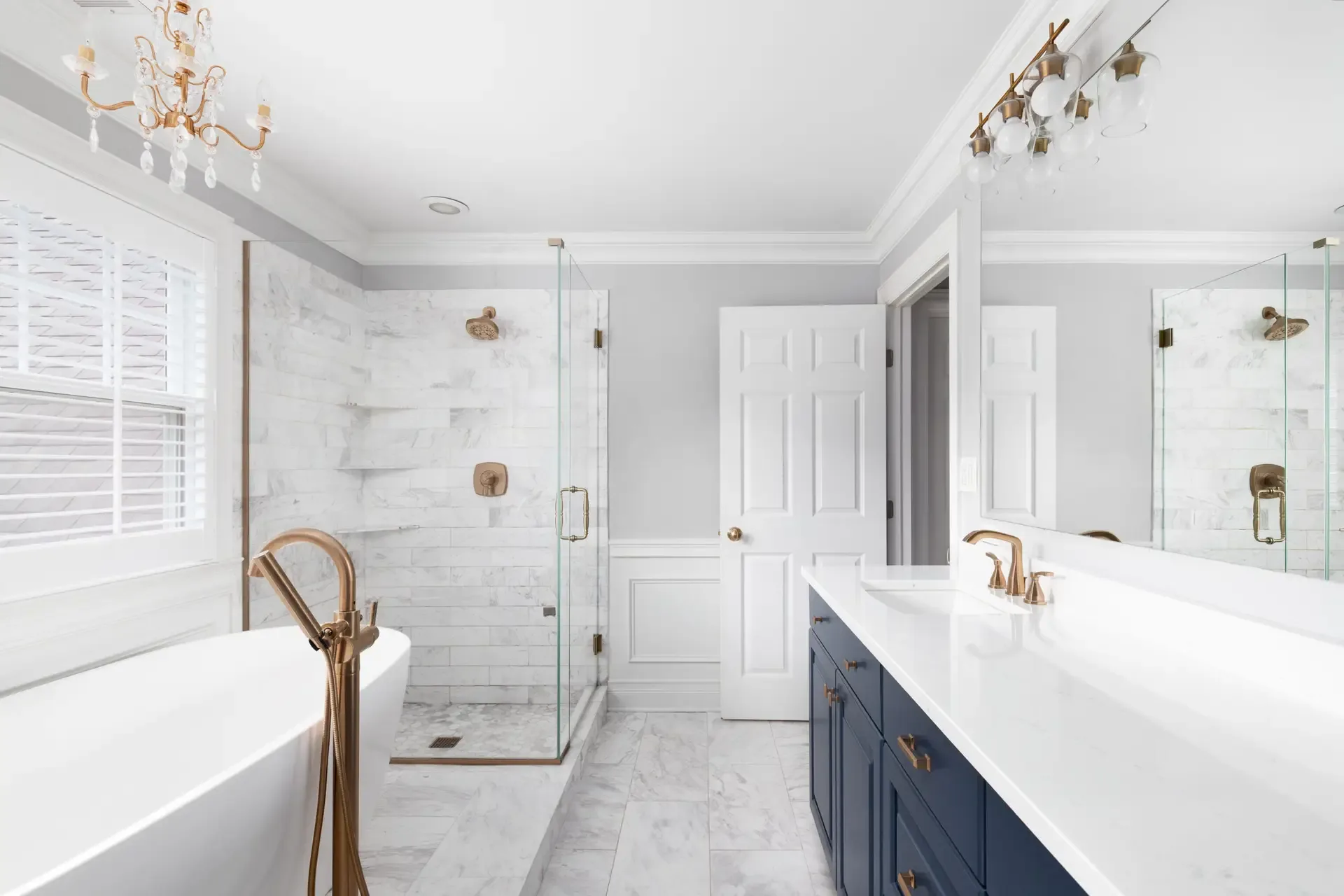 A bathroom with a freestanding tub, glass shower enclosure and a navy vanity