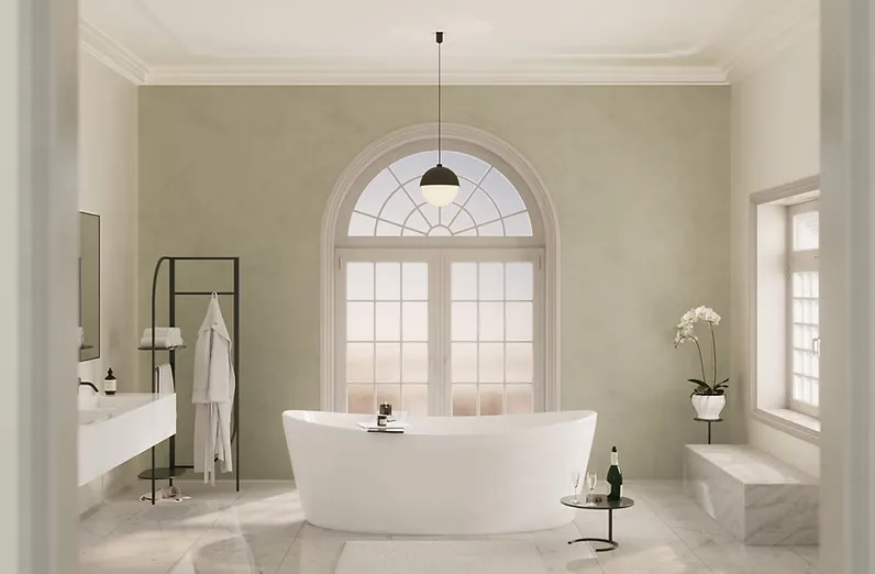 A bathroom with a freestanding tub set beneath a tall arched window
