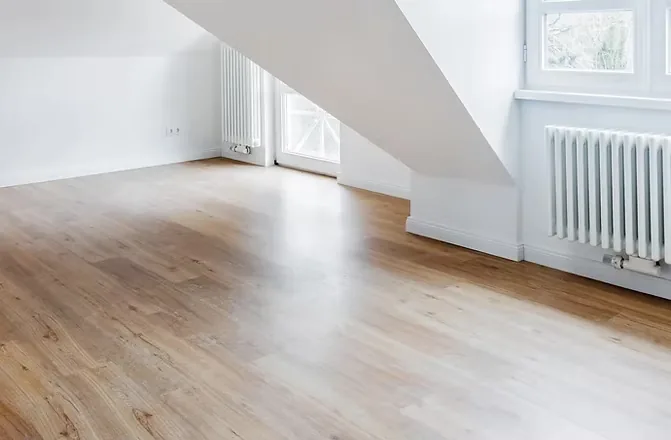 An empty room with newly laid wood-plank flooring running to the window