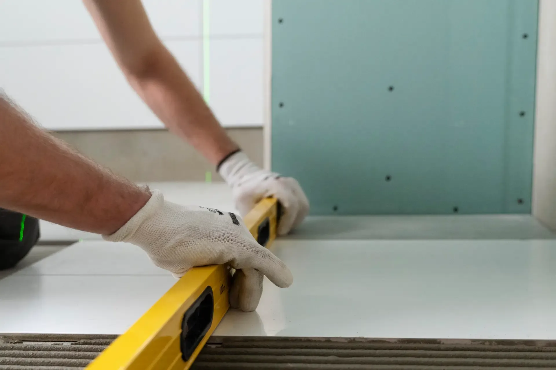 A tiler setting a large-format floor tile and checking it with a spirit level