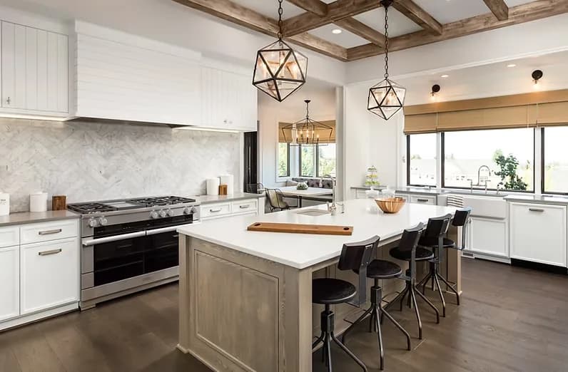 A large white kitchen with a timber-beamed ceiling, wood island and counter seating