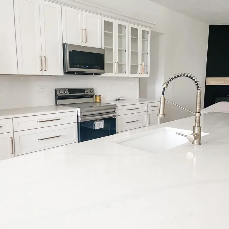 A compact white kitchen with quartz counters, an undermount sink and a pull-down faucet