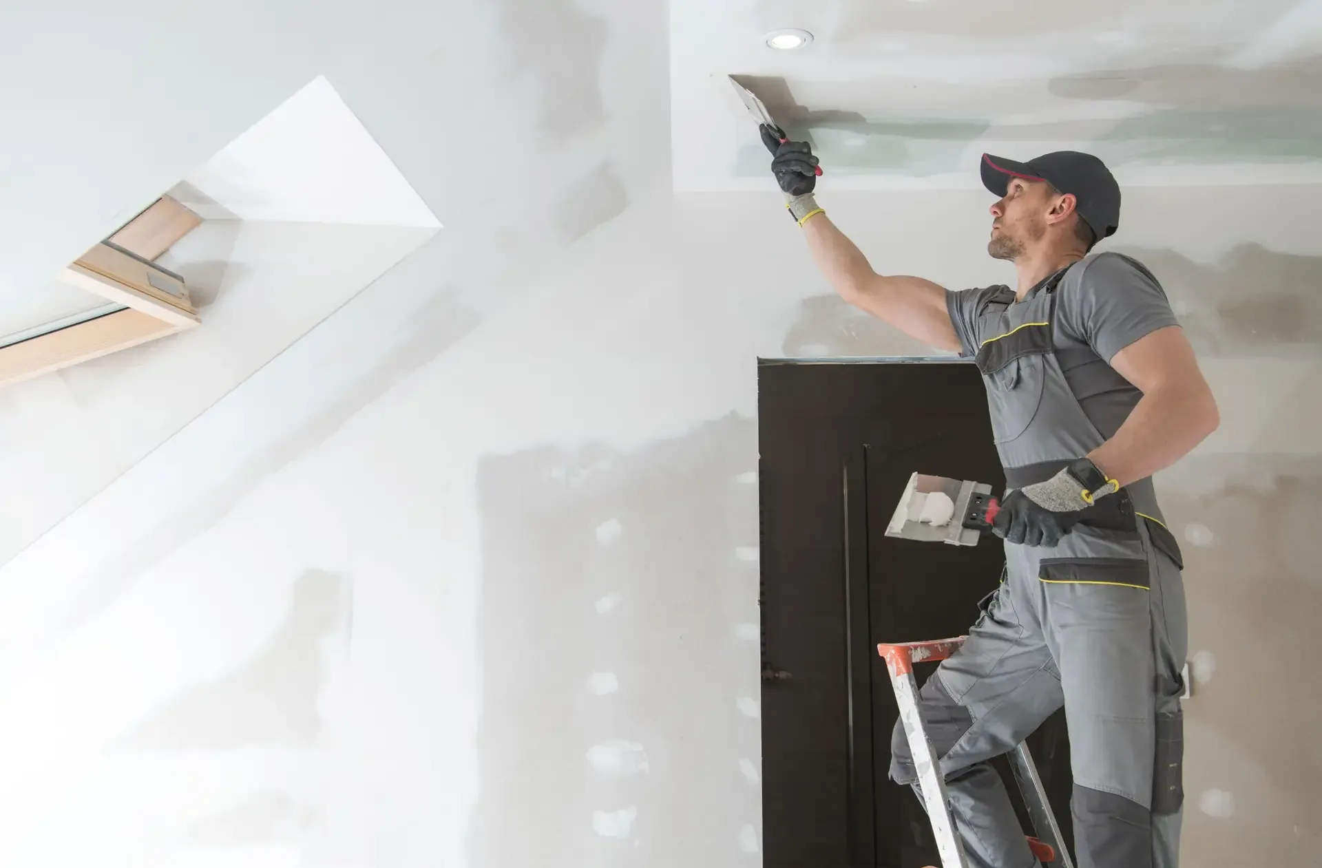 A tradesman skim-coating a wall smooth with a trowel