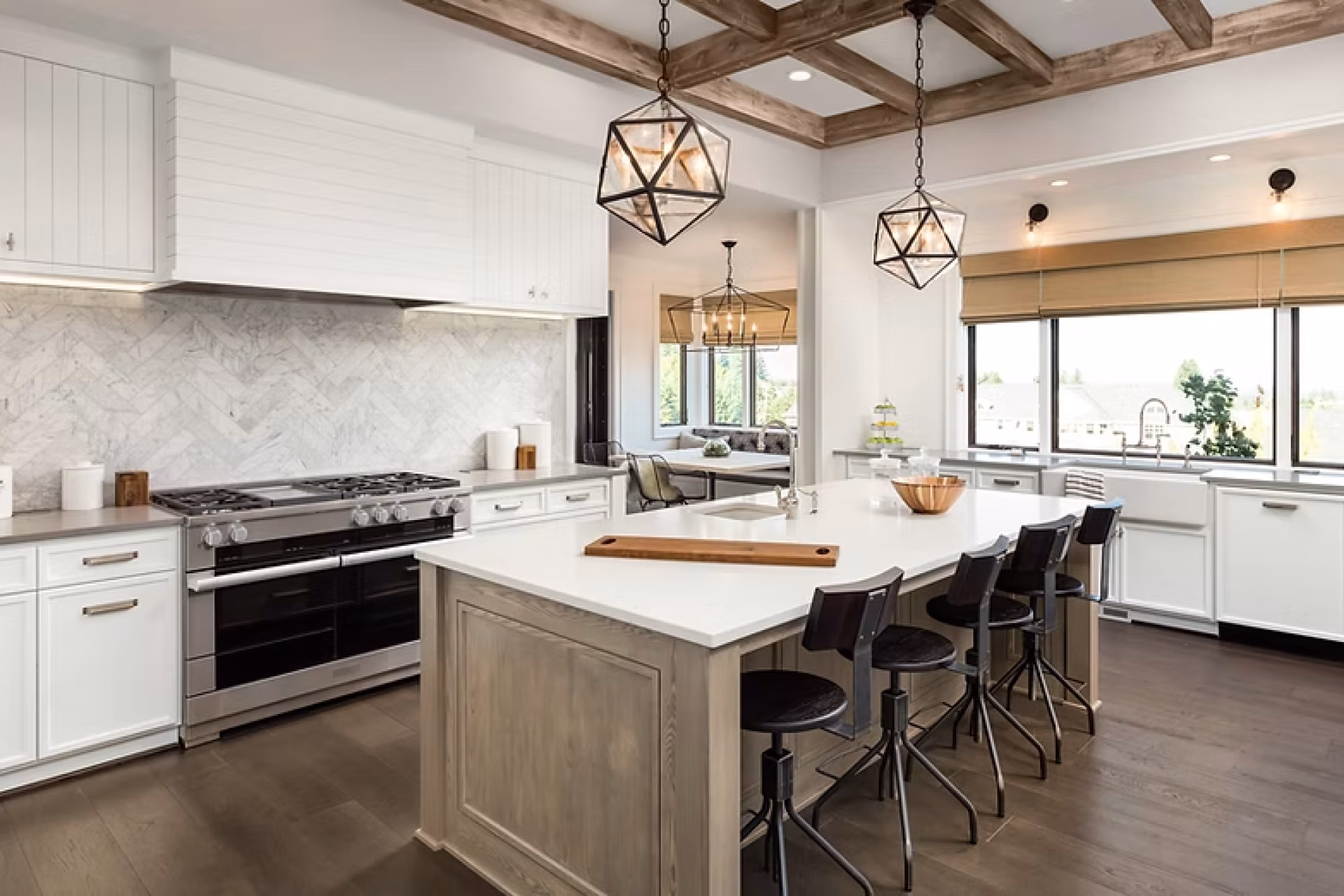 Open kitchen remodel with large island, wood ceiling beams, and herringbone marble backsplash by GIL Renovation Services in Jacksonville.