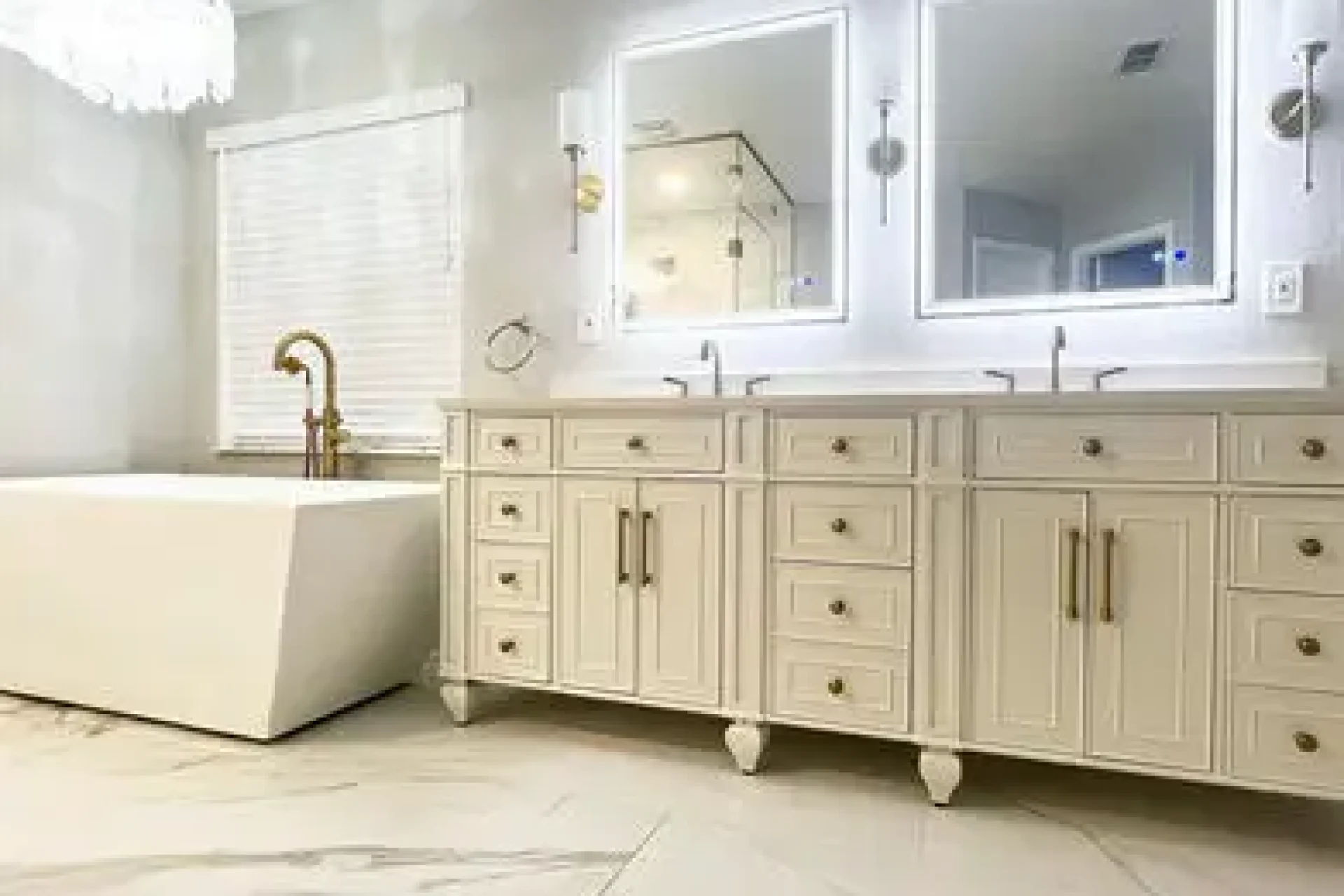 Elegant bathroom remodel with chandelier, dual mirrors, and freestanding tub by GIL Renovation Services.