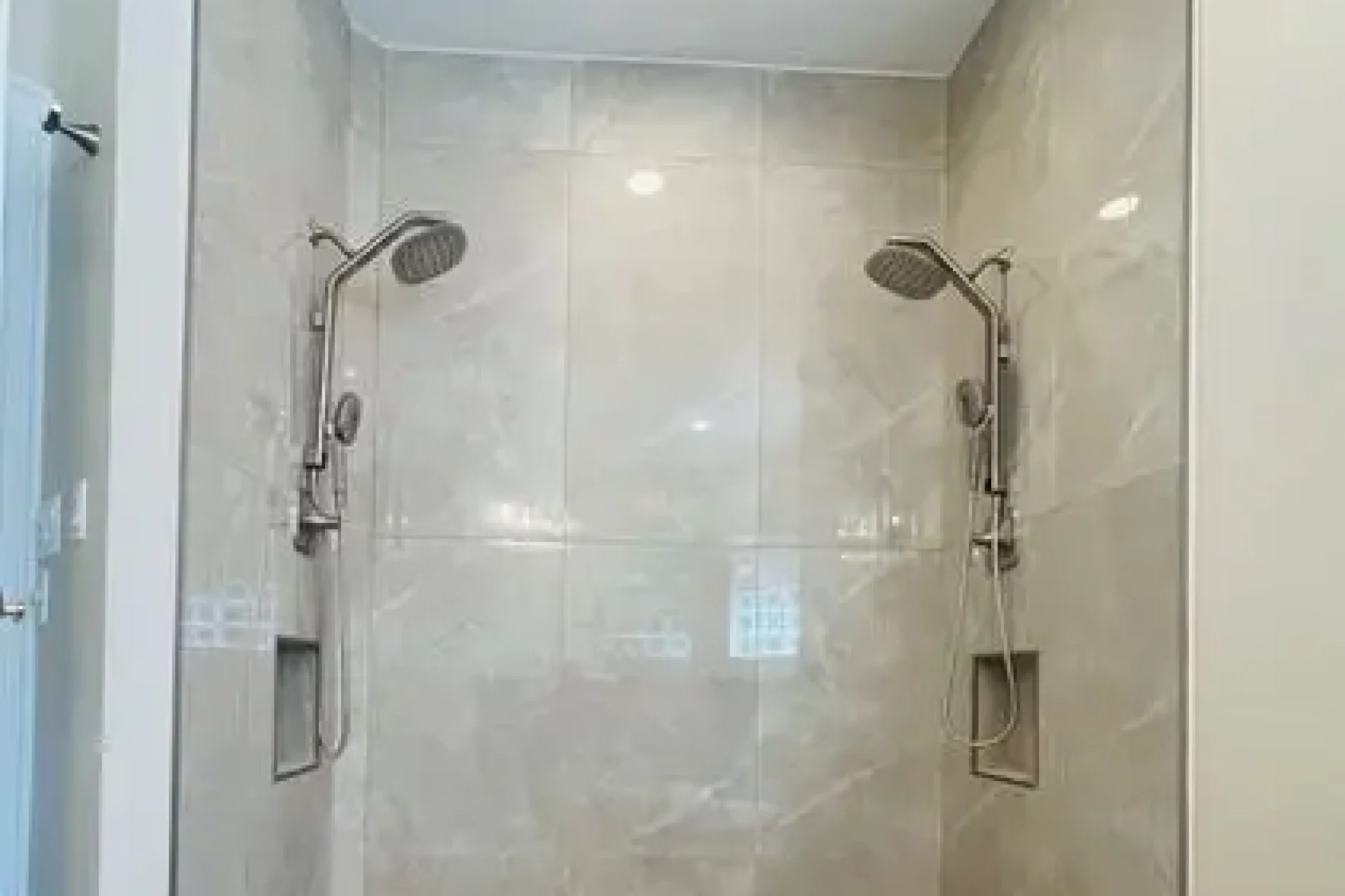 Dual walk-in shower with beige tile and mosaic floor installed by GIL Renovation Services in North Florida.